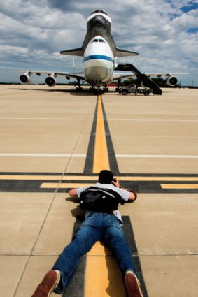 A photographer gets down low for a shot of the Space Shuttle Discovery after it's final landing on the back of a NASA's Boeing 747 Shuttle Carrier Aircraft( at Washington, Dulles International airport.