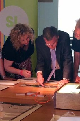 Artist Jon Barlow Hudson (right), Arts Minister Ian Walker and State Librarian Janette Wright look at the documents.