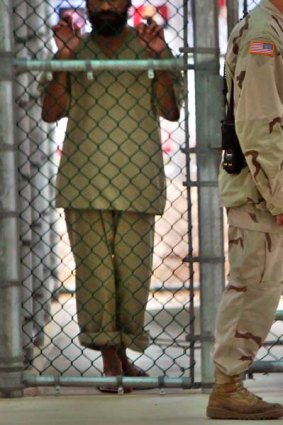 A detainee looks on  as a US military guard walks past the grounds of the maximum security prison at Camp 5 in Guantanamo Bay.