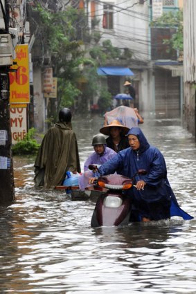 A man pushes his motorbike along a flooded street in Hanoi.
