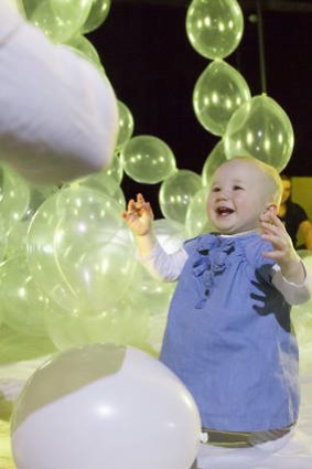 A baby interacts with balloons during a performance of <i>How High the Sky</i>.