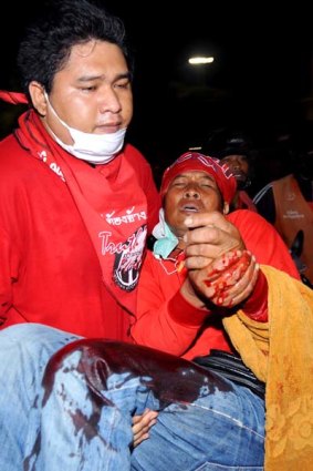 A supporter of ousted premier Thaksin Shinawatra carries an injured compatriot from clashes with security forces during an anti-government protest in Bangkok.
