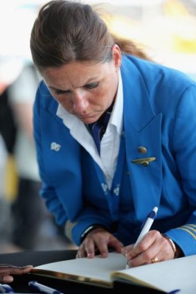 A KLM employee signs a book of condolence at the entrance to Schiphol Airport in memory of flight MH17.