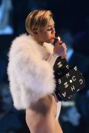 Singer Miley Cyrus smokes on stage after receiving the Best Video award during the 2013 MTV Europe Music Awards.