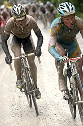 Mud-caked Cadel Evans (left) and Alexandre Vinokourov head for the finish in stage seven.