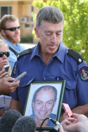ACT Firefighter Ged Morrison holding a photo of colleague David Balfour.