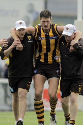 Hawthorn ruckman Simon Taylor is escorted from the field after hurting his ankle.