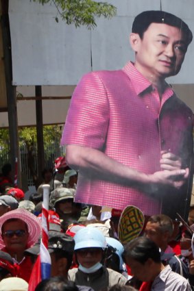 Supporters of ousted Thai prime minister Thaksin Shinawatra carry his image as they leave Government House.