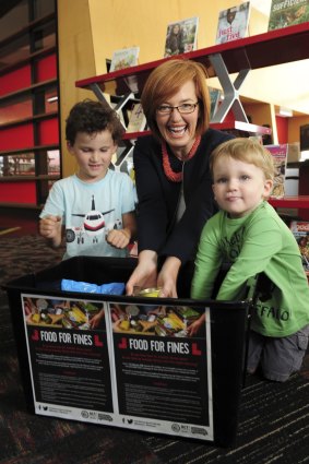 Minister for Municipal Services Meegan Fitzharris at the Gungahlin Library. Book fees are being waived in return for food donations. Helping her are Eaden Chapman, 5, left, and Connor Chapman, 3, both of O'Connor.