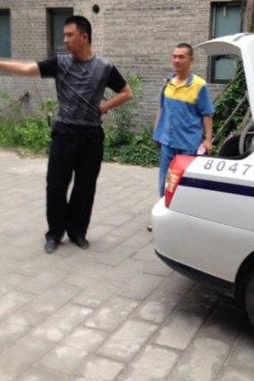 Detained: Australian artist Guo Jian, seen here in the yellow and blue uniform of a detainee, is escorted from his Beijing home by Chinese police after returning there briefly on Friday, June 6.