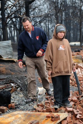 Khyle Vandenberk stands in the rubble of his house with chaplain Jeff Lampard.