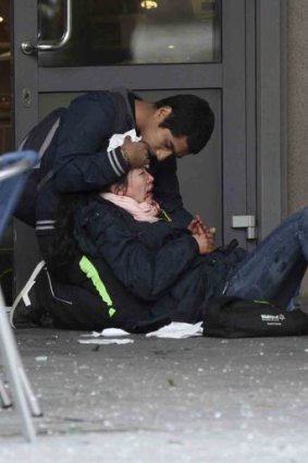 A passer-by comforts an injured woman.