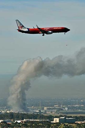 An aircraft takes off as the fire burns in the background.