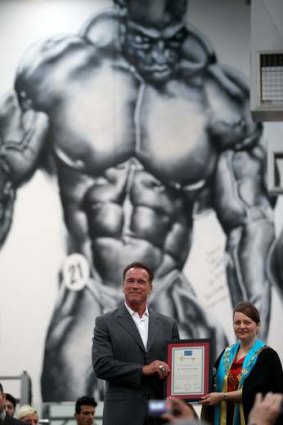 Arnold Schwarzenegger receives the keys to the city of Melton from Mayor Kathy Majdlik beneath a mural of bodybuilder Ronnie Coleman.