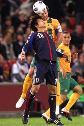 In for the fight ... Lucas Neill and Maeda Ryoichi of Japan compete for the ball.