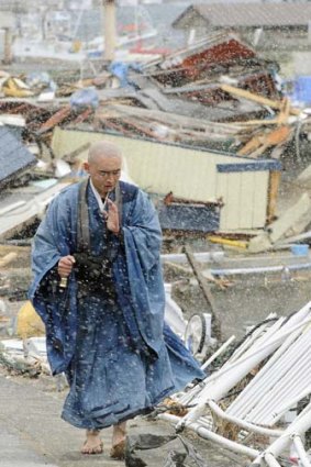 A Buddhist monk offers prayers as he walks through tsunami-stricken Yamada in northern Japan.