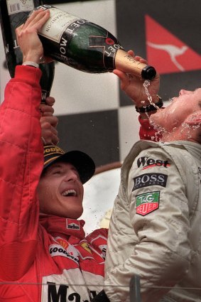 Michael Schumacher pours champagne on the winner of the 1997 Australian Grand Prix, David Coulthard.