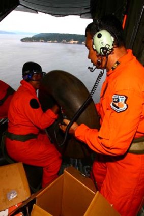 Indonesian Air Force personnel drop food and rubber floaters during search operation.