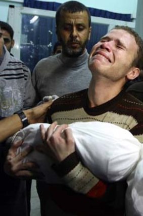 Jihad Masharawi weeps while he holds the body of his 11-month old son at Shifa hospital, who was killed in an Israeli air strike in Gaza.