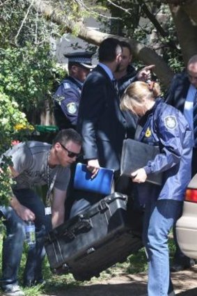 Police leave with what appears to be a sword after a raid in Sydney on Thursday.