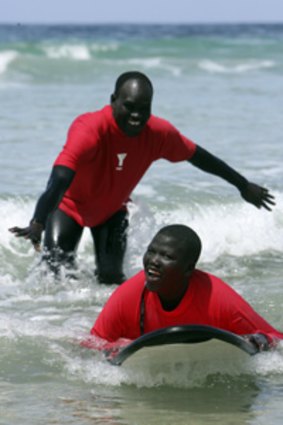 Top: Masud Majur, his son Paul, and (bottom) Abuk, 9, learn to surf at Phillip Island.
