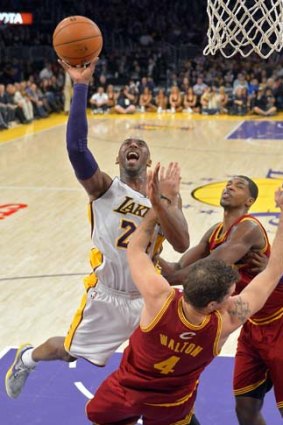 Los Angeles Lakers guard Kobe Bryant goes up for a shot as Cleveland Cavaliers forward Luke Walton (centre) falls and forward Tristan Thompson defends.