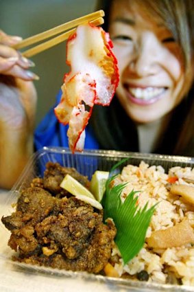 A Japanese woman uses chopsticks to pick up a slice of whale bacon  at a whale meat tasting in Tokyo.