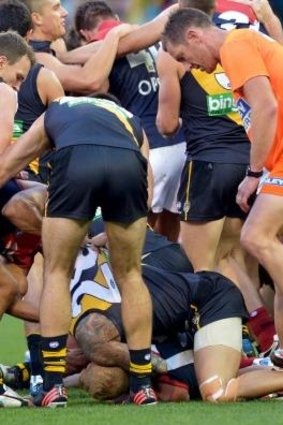 A Melbourne runner stands ont he foot of Richmond player Jake King.