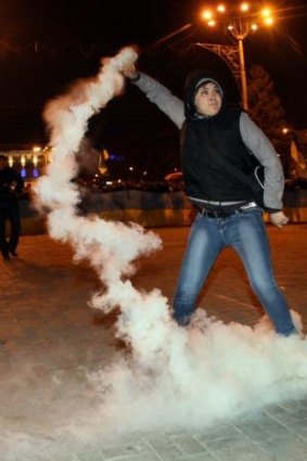 A pro-Ukrainian protester in Donetsk throws back a smoke bomb at pro-Russian protesters.