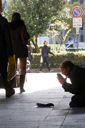 A man begs for money in front of a bank in Milan, Italy, where borrowing rates have spiked.