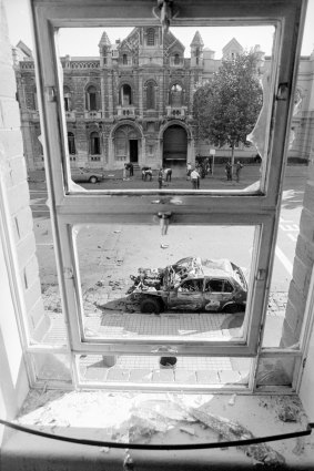 Russell Street bombing: A shattered first-floor window frames one of the burnt-out cars on Russell Street.