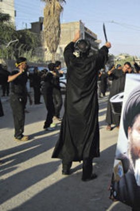 Willing spirits … an Iraqi youth in Baghdad holds a placard of radical Shiite cleric Muqtada al-Sadr.