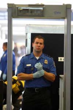 A TSA agent waits for passengers to pass through a magnetometer at Los Angeles International Airport.