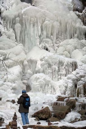 A hiker  pauses in front of a frozen waterfall in eastern France.
