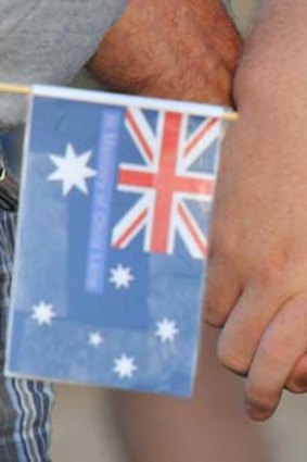 United in grief: Two mourners in Duncan hold an Australian flag bearing Chris Lane's name.