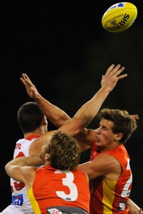 Hands up: Gold Coast duo David Swallow (right) Jared Brennan compete for a mark with Swan Martin Mattner.