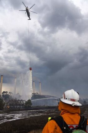 Firefighters on land and in a helicopter battle fire burning at the Hazelwood Coal Mine at Morwell, Australia.