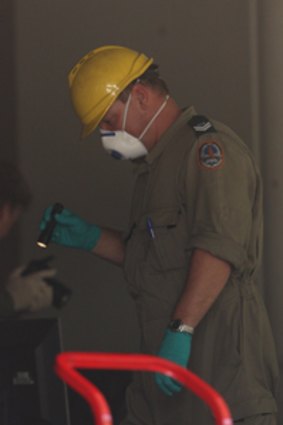 A fire investigator probes Darwin building after a fiery trolley was pushed through its doors. Photo: Glenn Campbell.