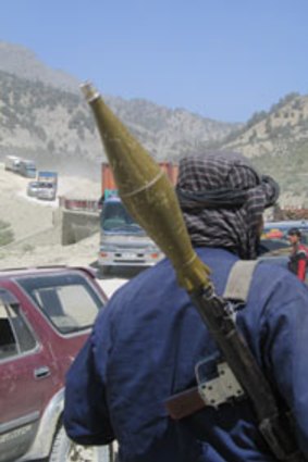 Rocky progress...an Afghan with a rocket-propelled grenade launcher watches traffic on the Khost-Gardez road.