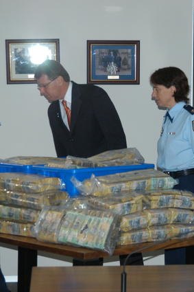 Cash haul ... police examine one of the syndicate's hoards of money found in numerous raids.