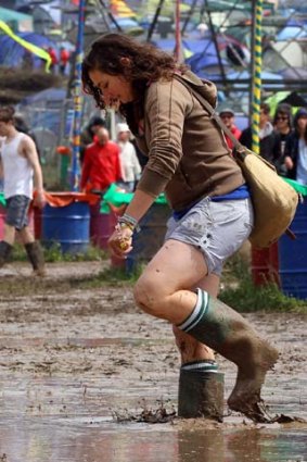 A gum-booted festival goer sloshes through the Glastonbury mud.