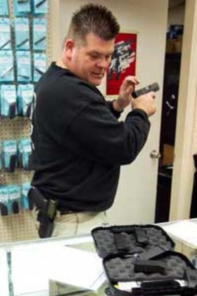 Greg Wolff takes a look at a customer's Glock semi-automatic pistol at his shop in Phoenix.