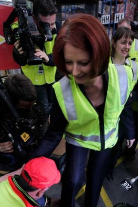 Fairytale ending ... the Prime Minister, Julia Gillard, is assisted by worker Rob Stewart after the PM's shoe fell off during a tour of the Linfox Distribution Centre in Altona, Victoria, yesterday.