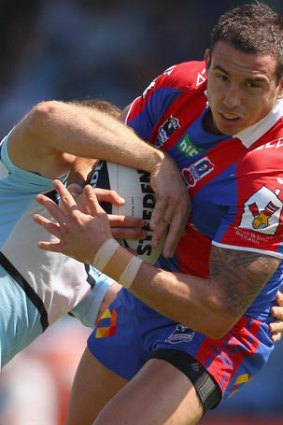 Darius Boyd of the Knights is tackled by a Cronulla Sharks player.