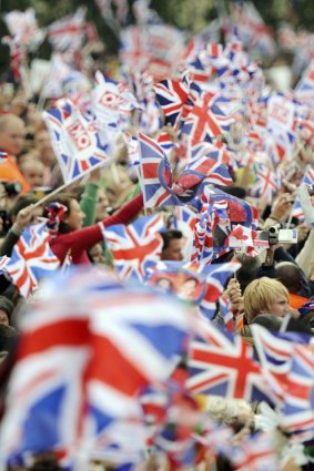 People wave British flags outside Buckingham Palace.