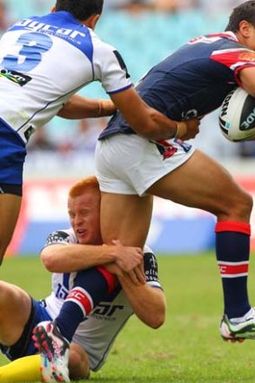 Out . . . Roosters player Sam Perrett is tackled yesterday.