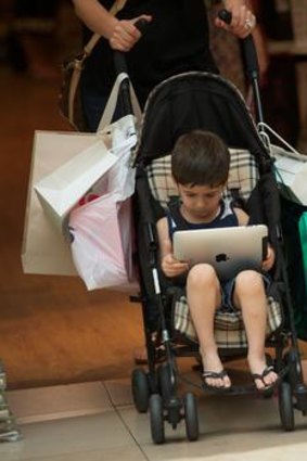 A young boy copes with Christmas shopping madness at Chadstone with an iPad.