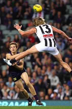Getting the jump: Magpie Dale Thomas takes the high road as Docker Nat Fyfe tries to handball last night at Patersons Stadium.