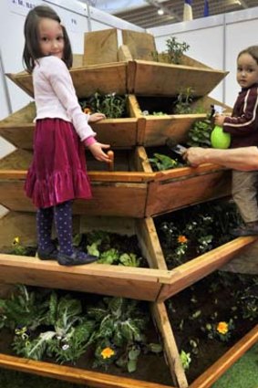 France's Jean-Marc Batard poses with his children next to his invention, an easy-reach pyramid garden which saves water.