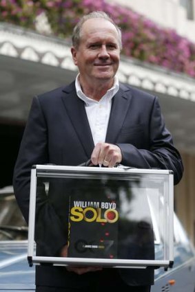 Author William Boyd poses with one of the first copies of his new James Bond book 'Solo,' in front of a Jensen car outside the Dorchester Hotel, both of which feature in the book, in London September 25, 2013.